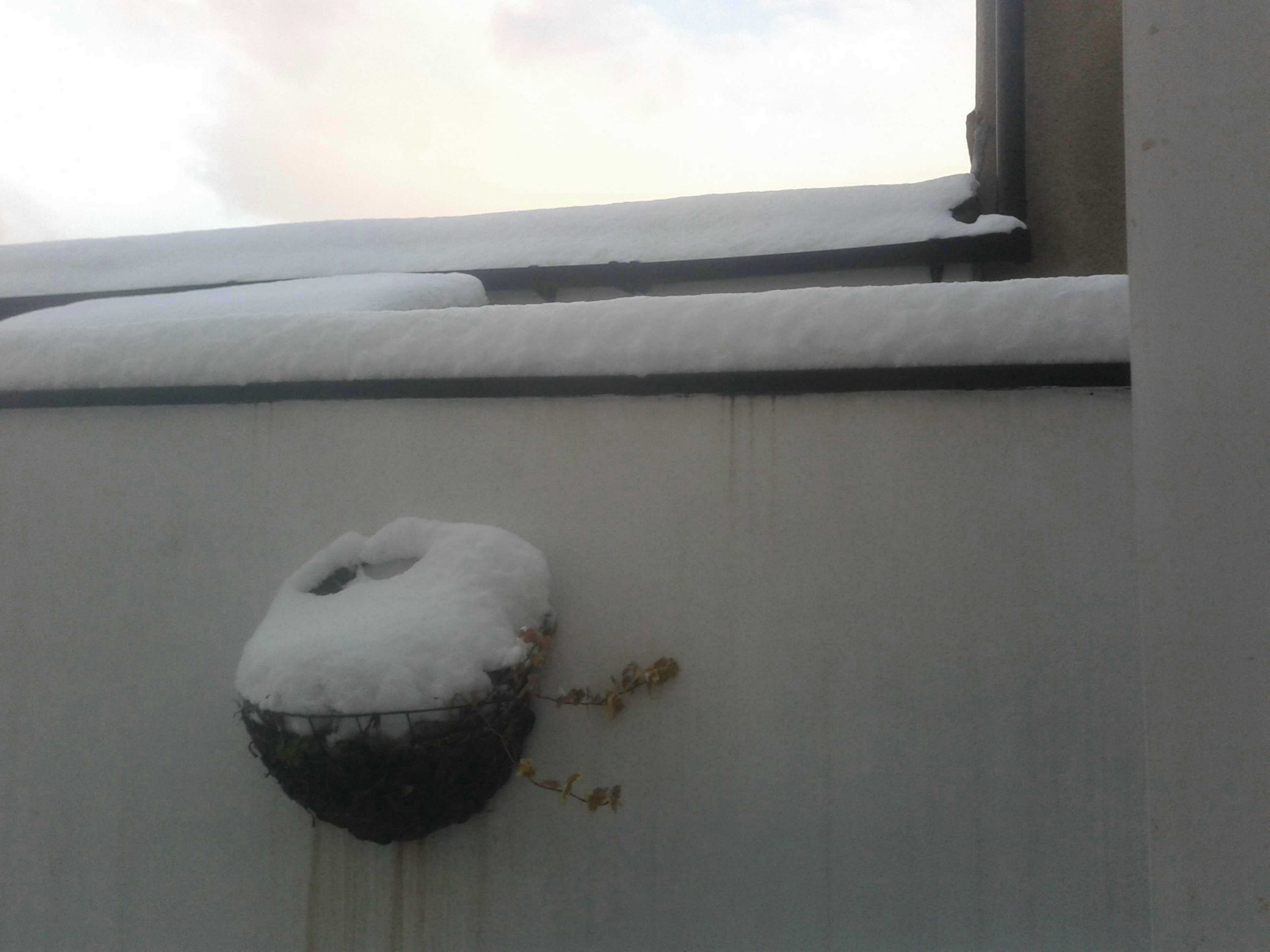 A wall painted white, with a basket covered with snow.